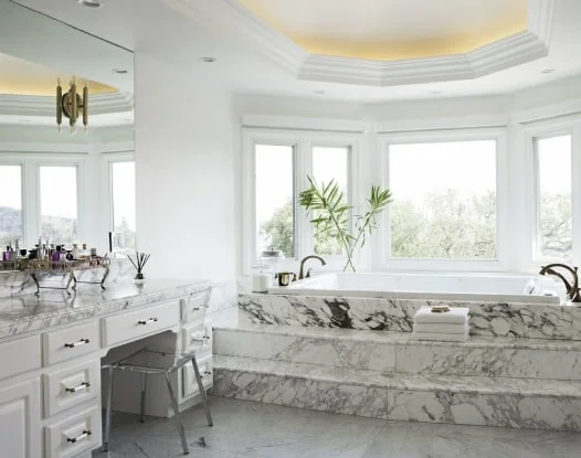 Luxurious marble bathroom with large windows and elegant decor.