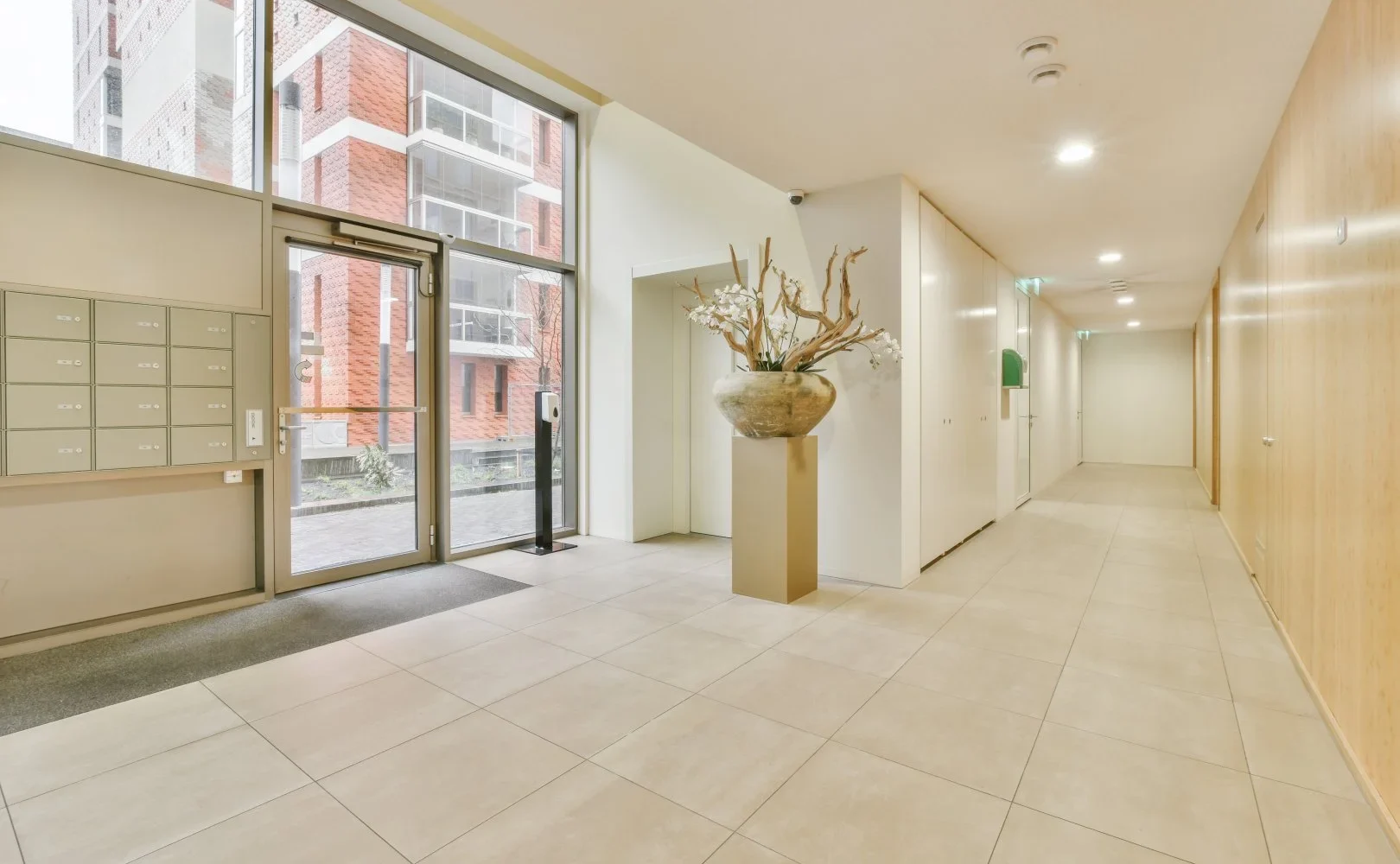 Modern apartment hall with large windows and decorative vase.