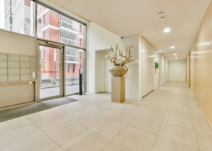 Modern apartment hall with large windows and decorative vase.