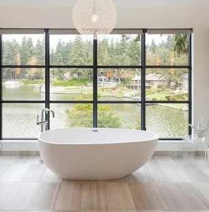 Modern bathroom with a freestanding tub and large window view.