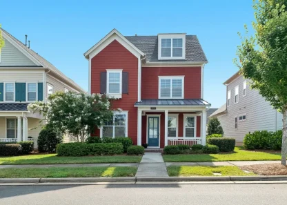 Charming red suburban house with white trim and a small front yard.