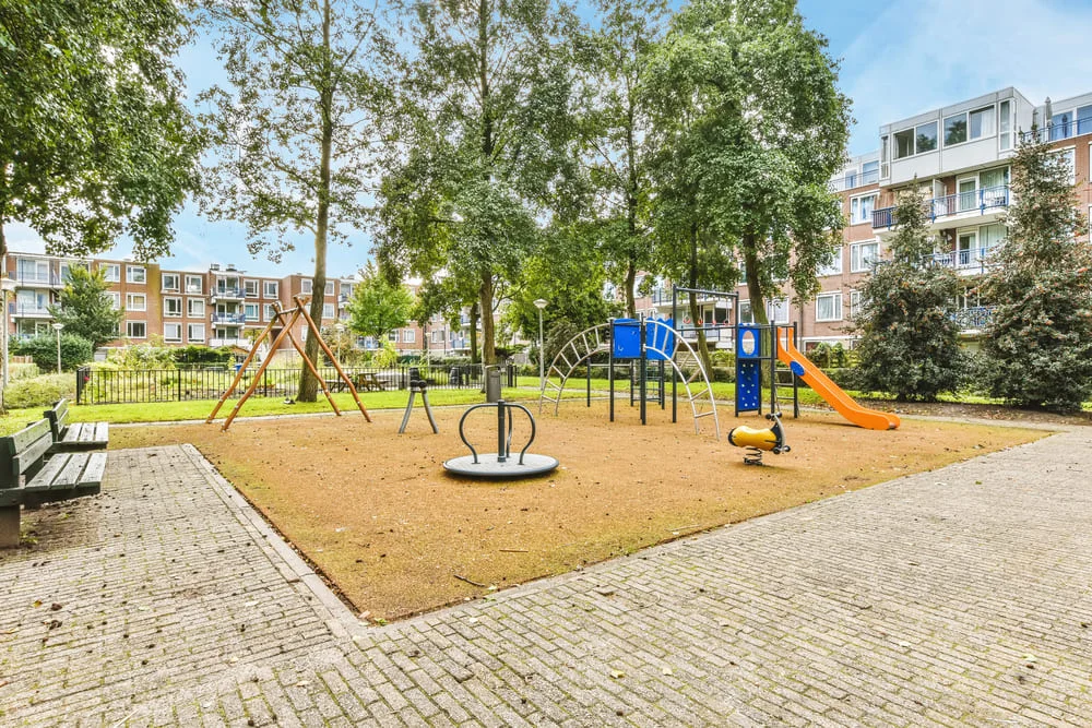 Urban playground with slides and climbing structures in a courtyard.